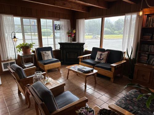 a living room with chairs and a table and a fireplace at Tillicum Beach Motel - Formerly Deane's Oceanfront Lodge in Yachats