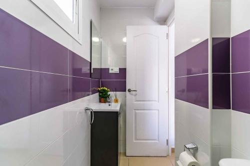 a purple and white bathroom with a sink and a door at Exclusive Deluxe Apartment - Fuengirola Beachfront in Fuengirola