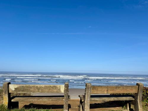 a bench sitting on the beach near the ocean at Tillicum Beach Motel - Formerly Deane's Oceanfront Lodge in Yachats