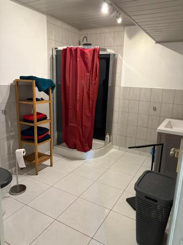 a bathroom with a shower with a red shower curtain at Le Champ du Bonheur in Esprels