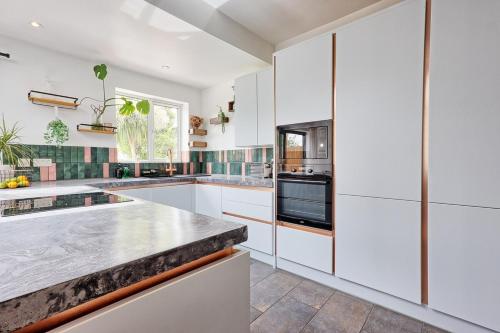 a kitchen with white cabinets and a counter top at Beautiful 5 bed house, relaxing garden and driveway parking 10 min to the beach in Southend-on-Sea