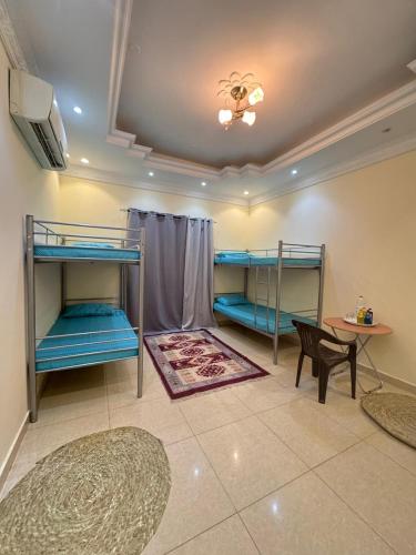 a room with three bunk beds and a table at Heritage Hostel Muscat in Muscat