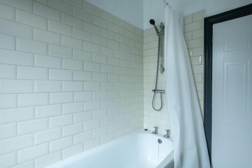 a white bathroom with a tub and a shower at 4BR Home in Great Location close to Transport in Liverpool