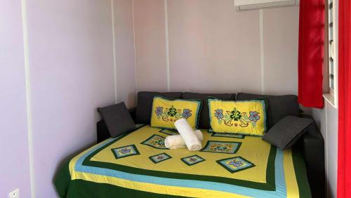 a small bedroom with a bed with colorful pillows at MOOREA - Bungalow Nauhei Surf Spot 2 in Haapiti