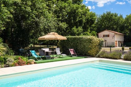 - une piscine avec des chaises, un parasol et une table dans l'établissement Maison de campagne - maeva home - Maison 4 pièces 6 personnes - Confort MAE-7261, à Carcans
