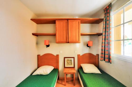 zwei Einzelbetten in einem Zimmer mit Fenster in der Unterkunft La résidence du Lac - maeva Home - Appartement 2 pièces 4 personnes - Sélection MAE-0263 in Monflanquin