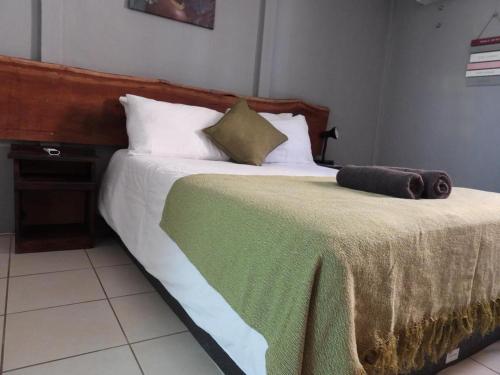 a bed with a green and white blanket on it at Carlo's Mountain Lodge in Usakos