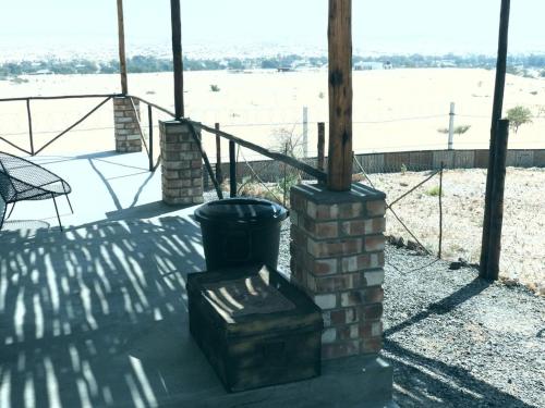 a porch with a brick stove with a view of a field at Carlo's Mountain Lodge in Usakos