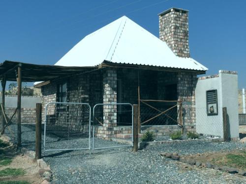 a small brick building with a white roof at Carlo's Mountain Lodge in Usakos