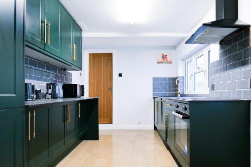 a green kitchen with black cabinets and appliances at Hyacinth Apartments - Hot Tub Garden Escape - Adults only in Brighton & Hove