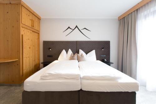 a bedroom with a large white bed with white pillows at Ferienhotel Bergland in Arzl im Pitztal