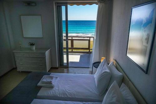 a bedroom with a bed and a view of the ocean at Sunny Bay Beachfront Retreat in Mola Kalyva