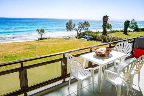 a table and chairs on a balcony with the beach at Sunny Bay Beachfront Retreat in Mola Kalyva