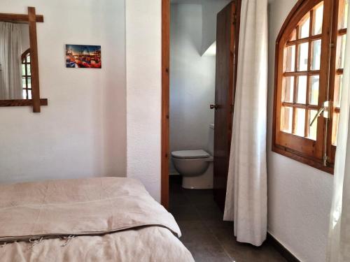 a bedroom with a bed and a toilet and a window at Villa de Gracia Casa 4 in Tordera