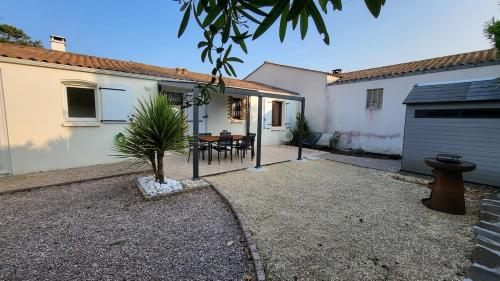 ein Hinterhof eines Hauses mit einem Tisch und einer Garage in der Unterkunft Maison Quartier du Phare in La Tranche-sur-Mer