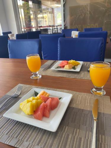 two plates of fruit on a table with two glasses of orange juice at Hotel Down Town Cabrera in Cabrera