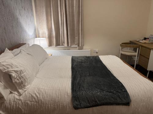 a bedroom with a bed with a black blanket on it at LHChomeway in Earley