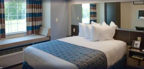 a hotel room with a large bed with white pillows at WeStay Suites Belle Chasse in Belle Chasse
