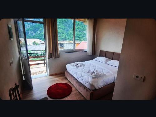 a bedroom with a bed and a large window at Mikel Center Theth Guesthouse in Shkodër