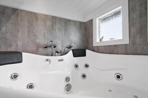 a white bath tub in a bathroom with a window at 090-Ringkobing-Klaegdalen-9 in Ringkøbing