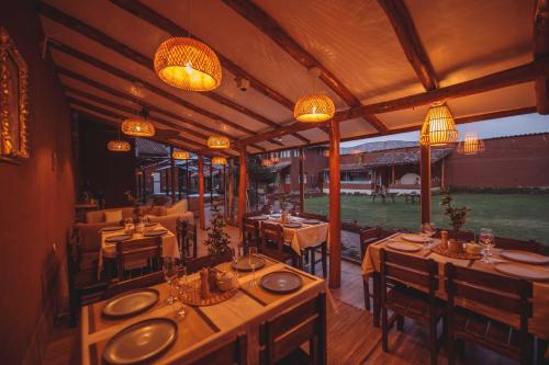 a restaurant with tables and chairs and chandeliers at Kutimuy Lodge in Urubamba