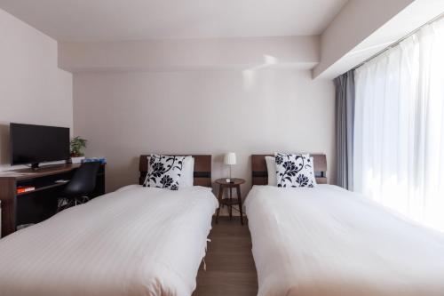 two beds in a room with a desk and a tv at LANG HOTEL Kameido - Vacation STAY 79388v in Tokyo