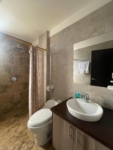 un bagno con lavandino, WC e specchio di Comfortable 3 bedroom house near the airport Quito and Portal a Calderón