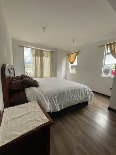 una camera con un grande letto e due finestre di Comfortable 3 bedroom house near the airport Quito and Portal a Calderón