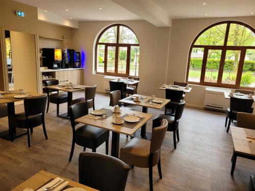 een restaurant met tafels, stoelen en ramen bij Sure Hotel by Best Western Saint-Quentin Ouest Le pot d étain in Holnon