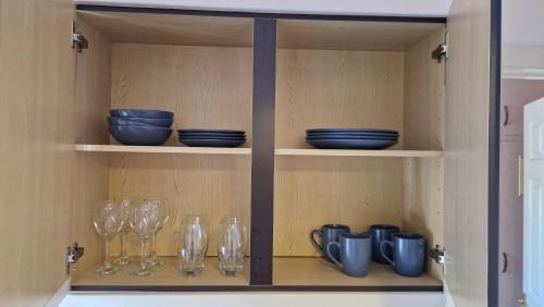 a cupboard with glasses and plates and bowls on it at 1-Bedroom Annexe in Brighton-Saltdean in Saltdean