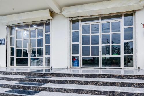 a white building with two windows and some stairs at Hotel O Shree Krishna Palace in Nilmatha