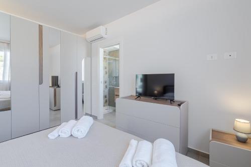 ein Schlafzimmer mit weißen Handtüchern auf einem Bett und einem TV in der Unterkunft Villa very close to Santa Maria Del Focallo beach blue flag with private pool in Santa Maria Del Focallo
