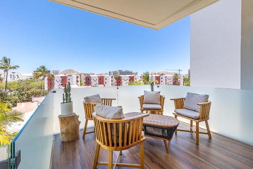 a room with chairs and a table on a balcony at Marea Walk to Medano Stylish Stay in Cabo in Cabo San Lucas
