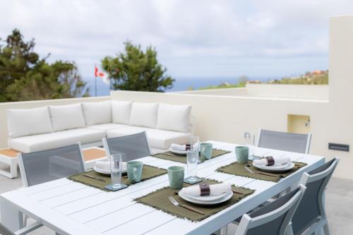 a white dining table with chairs and a white couch at Idônea in Ponta Garça