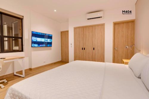 a bedroom with a large white bed and a tv at Magusan Holiday Rentals in Cali