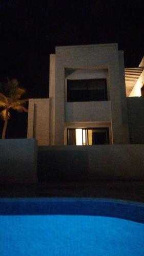una casa por la noche con una piscina delante en روتانا, en Salalah