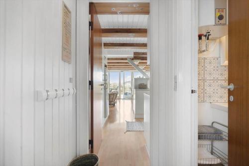 einen Flur mit weißen Wänden, Holzböden und einer Tür in der Unterkunft 260 Ringkøbing - Vestklitvej 13 in Klegod