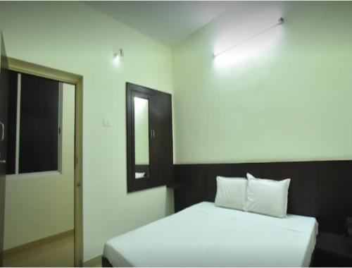 a bedroom with a white bed and a mirror at PRM Aruna Lodge in Erode