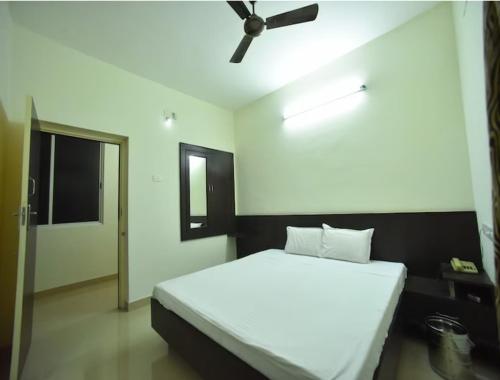 a bedroom with a white bed with a ceiling fan at PRM Aruna Lodge in Erode