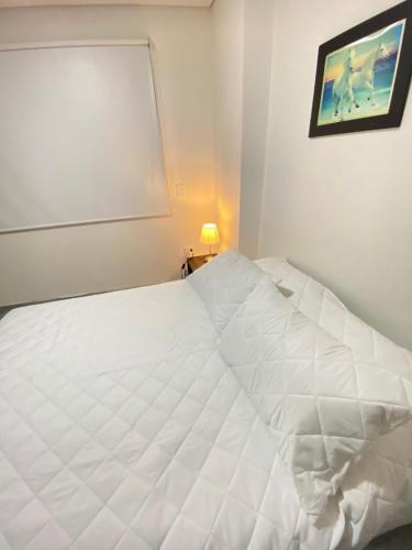 a white bed in a bedroom with a picture on the wall at Apartamento Centro Marinilla in Marinilla