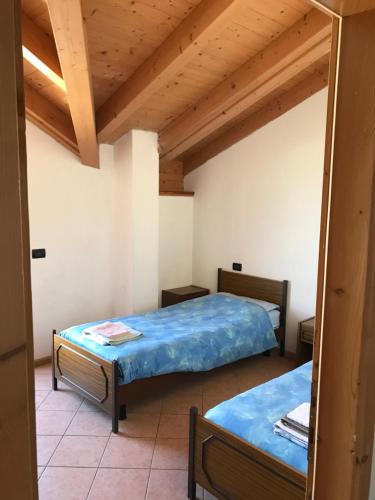 two beds in a room with wooden ceilings at Appartamento Widmann Silvano in Cles