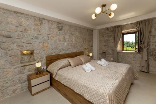 Un dormitorio con una cama y una pared de piedra. en Villa Mikić, en Klek