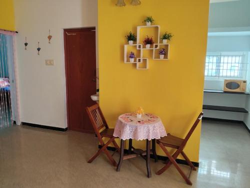 a table and chairs in a room with a yellow wall at A Cozy Homestay in Coimbatore in Coimbatore