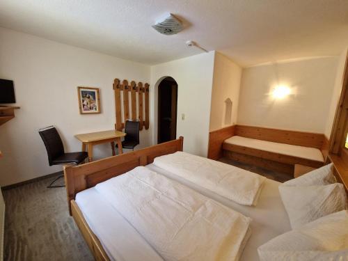 a bedroom with two beds and a table and a desk at Appartement St. Hubertus in Flirsch