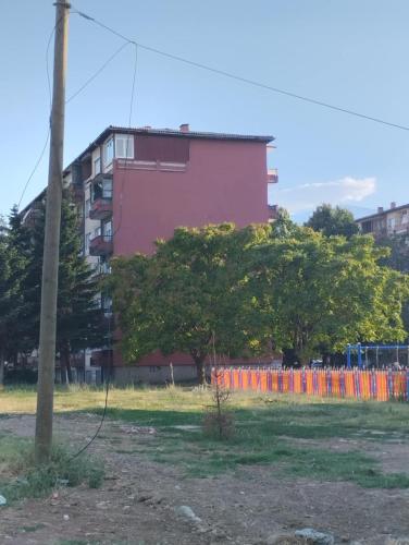 a pink building with trees in a field at Jakov's apartment in Bitola