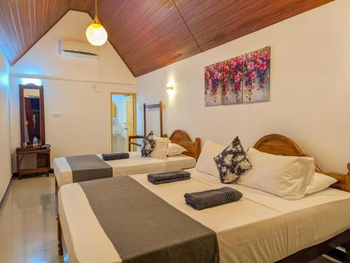 a room with three beds and a painting on the wall at Choona Lodge 'view of sigiriya & pidurangala with sunrise' in Sigiriya