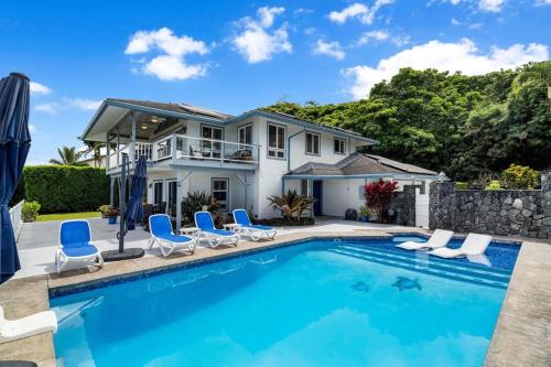 a swimming pool with chairs and a house at Honu O Kai (Turtle of the Sea) in Kailua-Kona