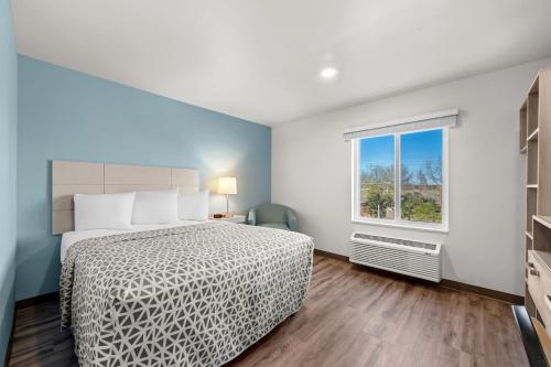 a bedroom with a bed and a window at WoodSpring Suites Charlotte - Arrowood in Charlotte