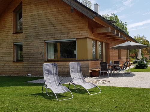 two chairs and an umbrella in front of a house at Apartmány Stachy Churáňov in Stachy