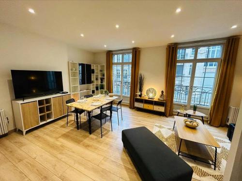 un grand salon avec une table et une télévision dans l'établissement L’etape des sacres, à Reims